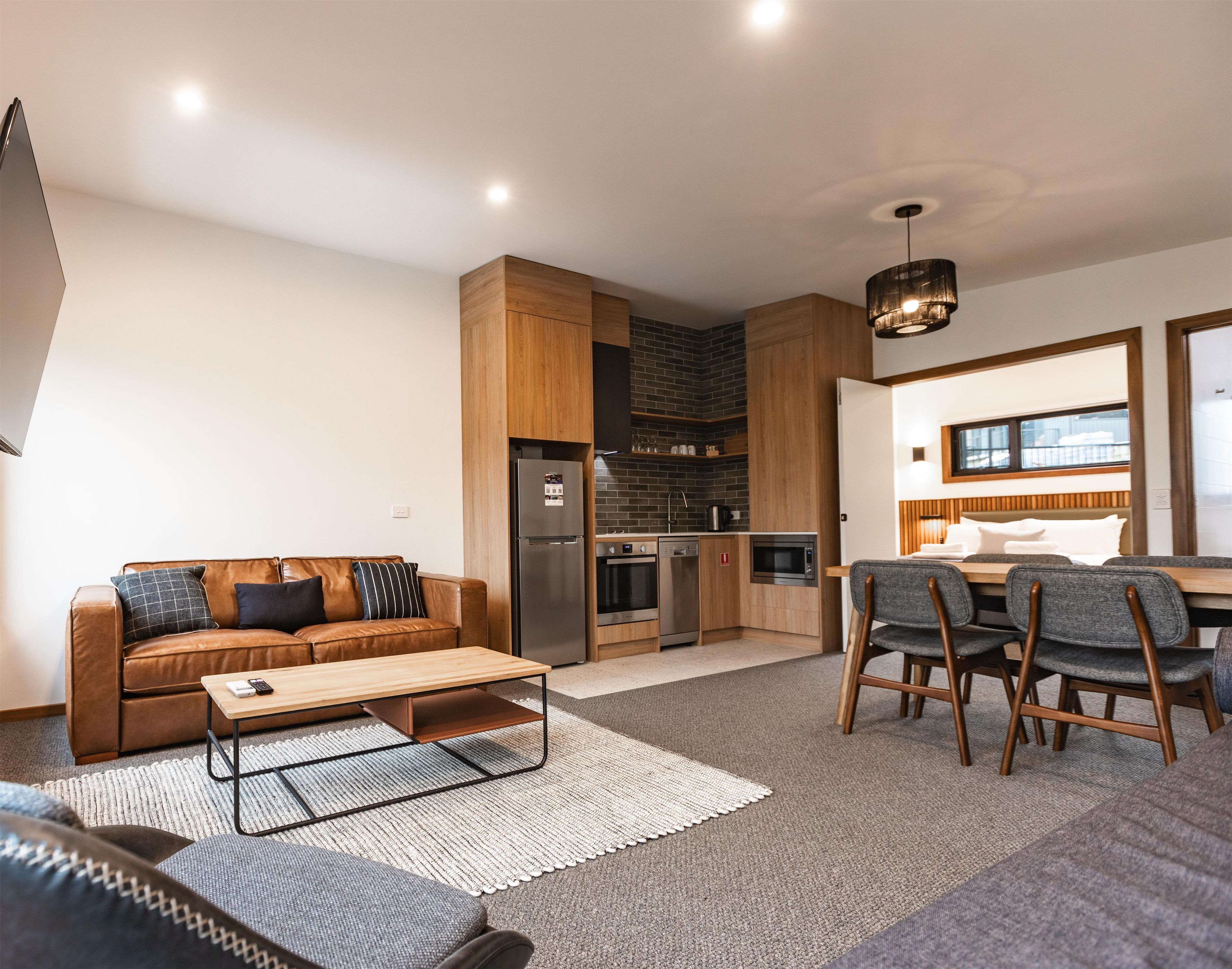 A modern living room with a sofa, coffee table, and dining area with chairs.