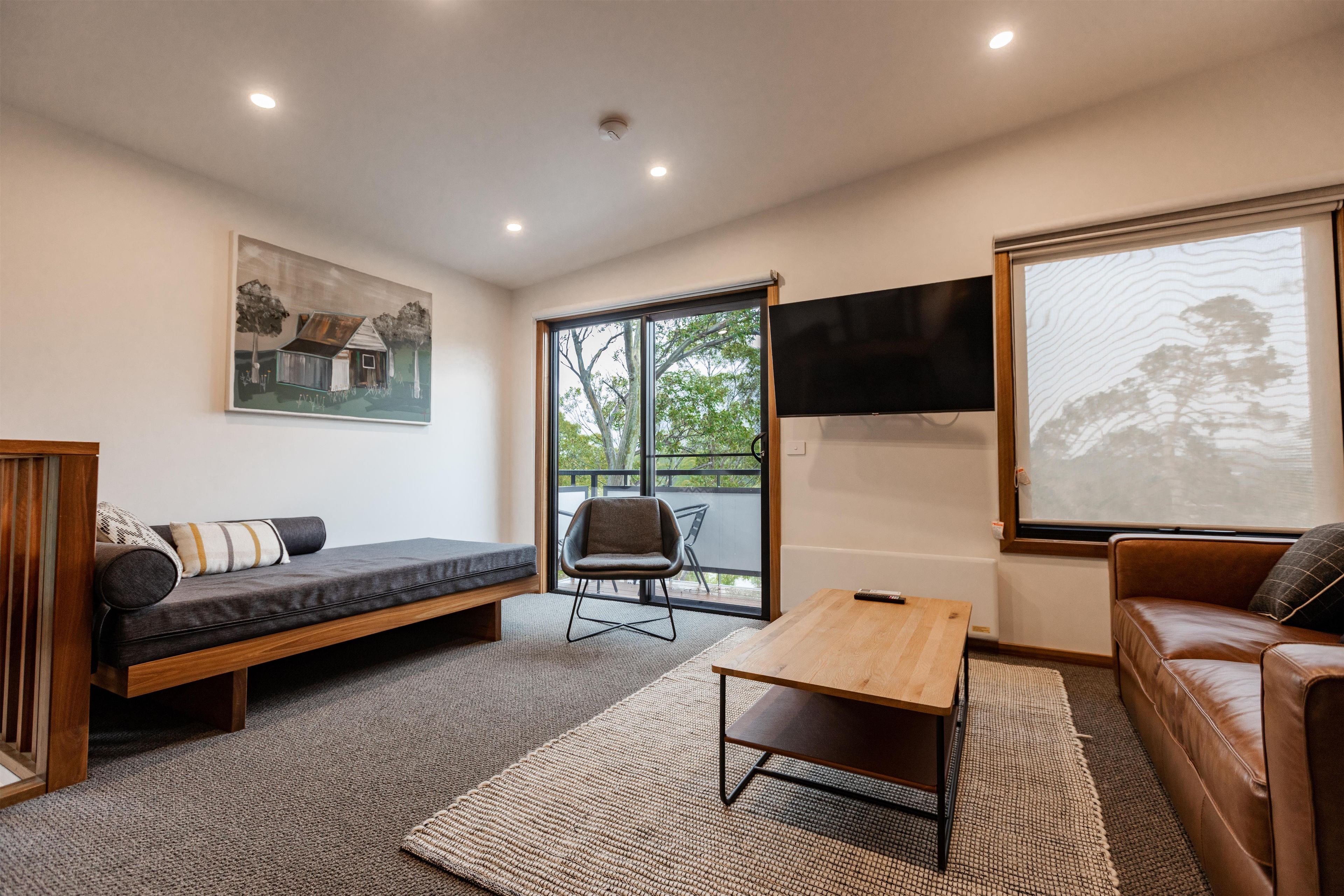 A modern living room with a sofa, a wooden coffee table, a TV, and a painting on the wall.