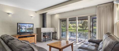 Un salon moderne avec une cheminée, un canapé en cuir, une table basse en bois et un téléviseur.