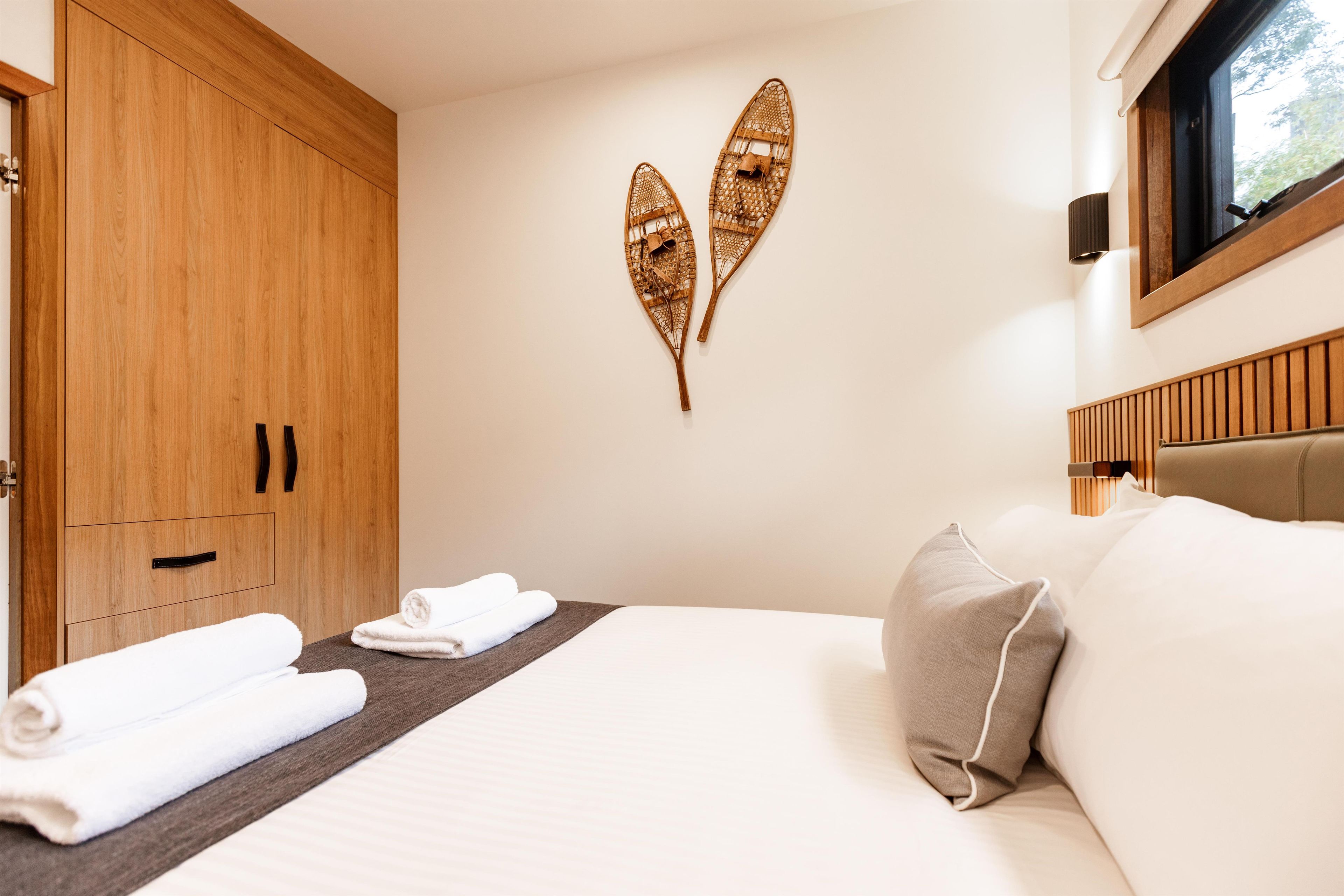 Een hotelkamer met een bed, een houten garderobe en decoratieve objecten aan de muur.