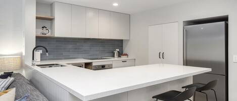 A modern kitchen with a large island, bar stools, and a built-in refrigerator.