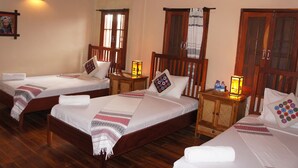 Habitación de hotel con dos camas individuales, cabeceros de madera, mesitas de noche con lámparas y un armario de madera.