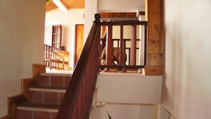Una escalera de madera con barandilla que lleva a una plataforma con vistas a una habitación.