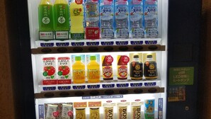 Un distributeur automatique proposant une variété de boissons et d’en-cas, notamment des produits de la marque Suntory.