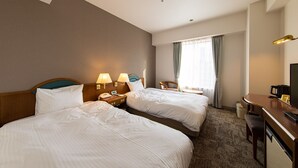 Une chambre d’hôtel avec deux lits, un bureau, une chaise, une télévision et une fenêtre avec des rideaux.