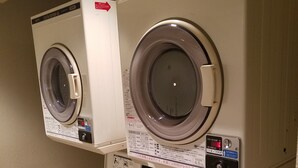Une laverie équipée de plusieurs lave-linge et sèche-linge, dont un modèle portant la mention « SÈCHE-LINGE CO/N 45 ».