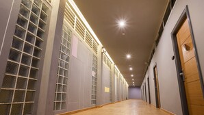 A hallway with wooden flooring, large windows with metal grilles, and wooden doors. - Admire Thonburi (Bangkok)