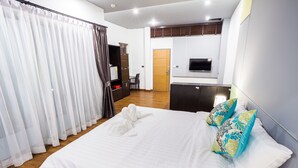 A hotel room with a large bed, a TV mounted on the wall, a desk, and a wardrobe. - Admire Thonburi (Bangkok)