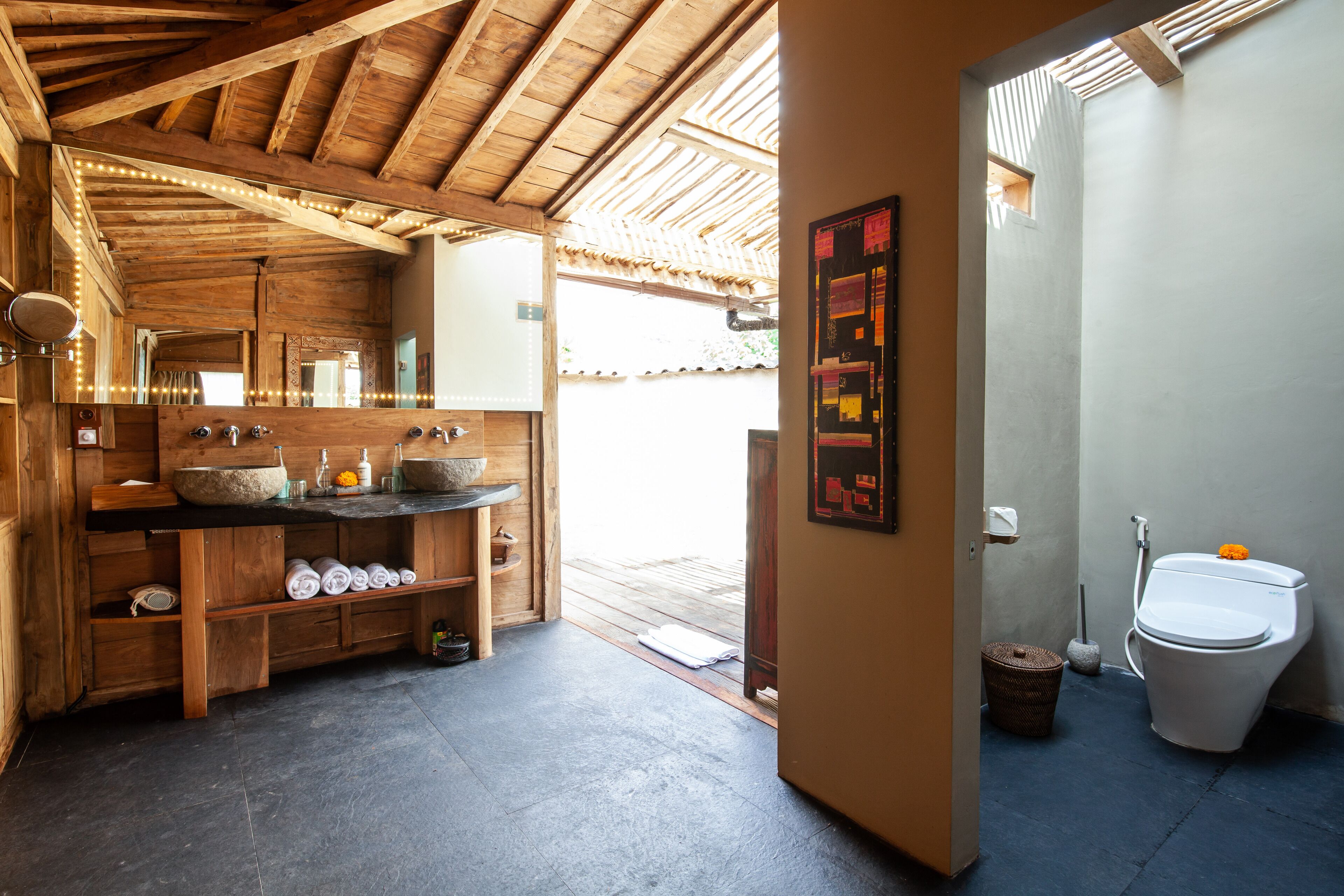 Een badkamer met een houten wastafelmeubel, een grote spiegel en een toilet.