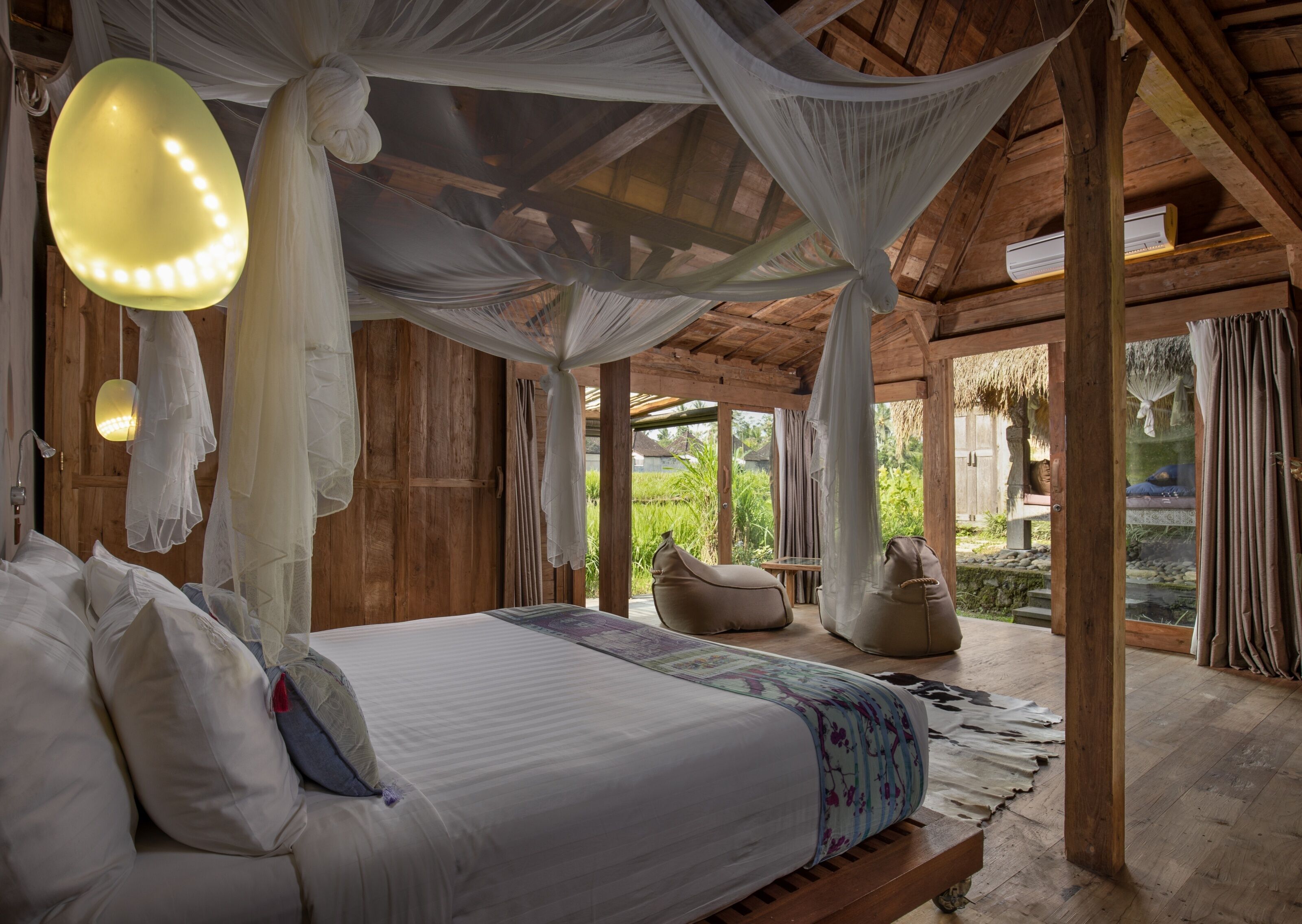 A spacious bedroom with a large bed, a canopy, and a view of a garden.