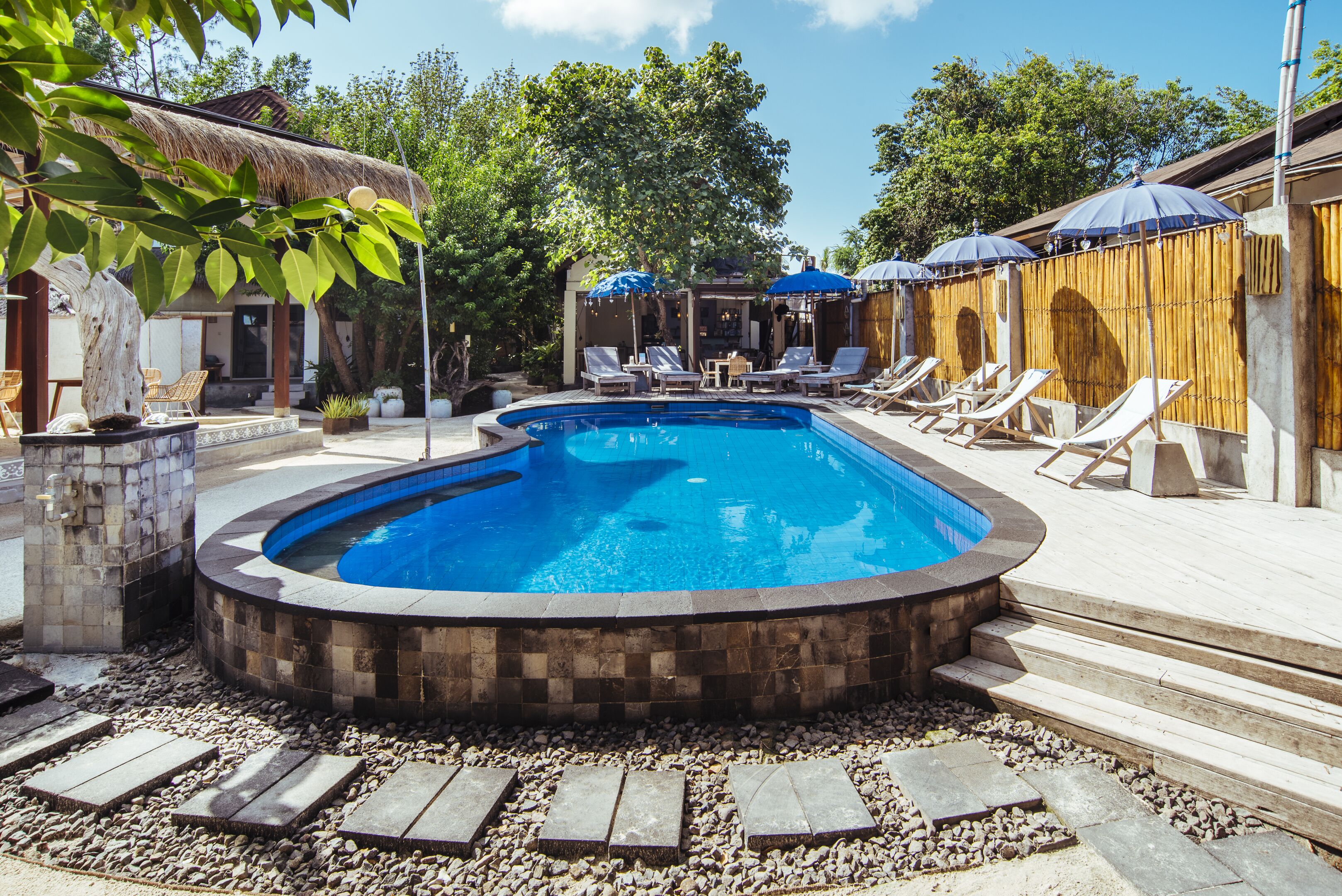 Una piscina al aire libre, sombrillas, sillones reclinables de piscina