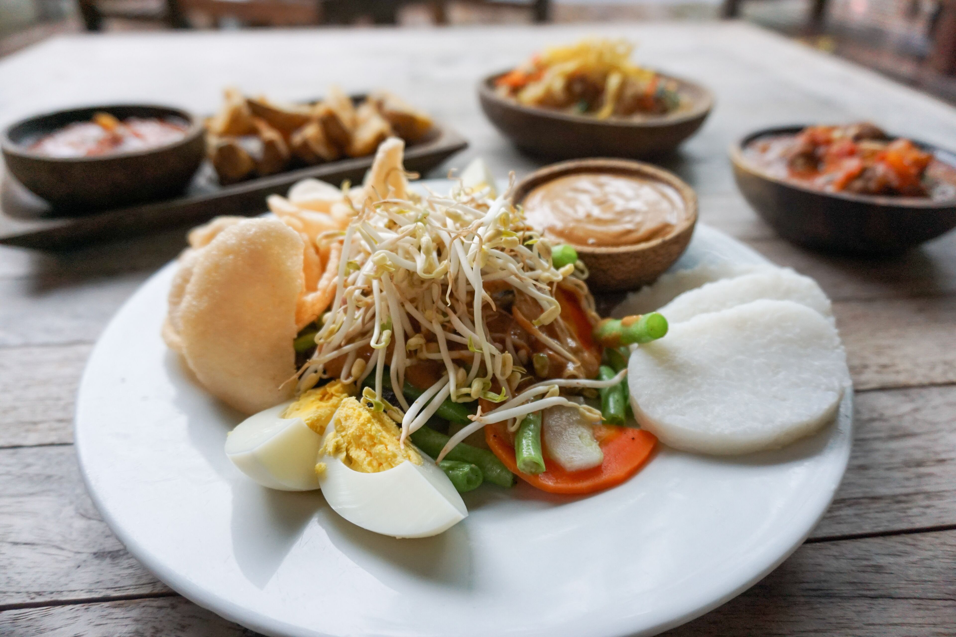 Un plato de comida con diversos platos, incluyendo un sándwich, huevos cocidos y verduras.