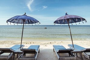 Am Strand, weißer Sandstrand, Liegestühle, Sonnenschirme