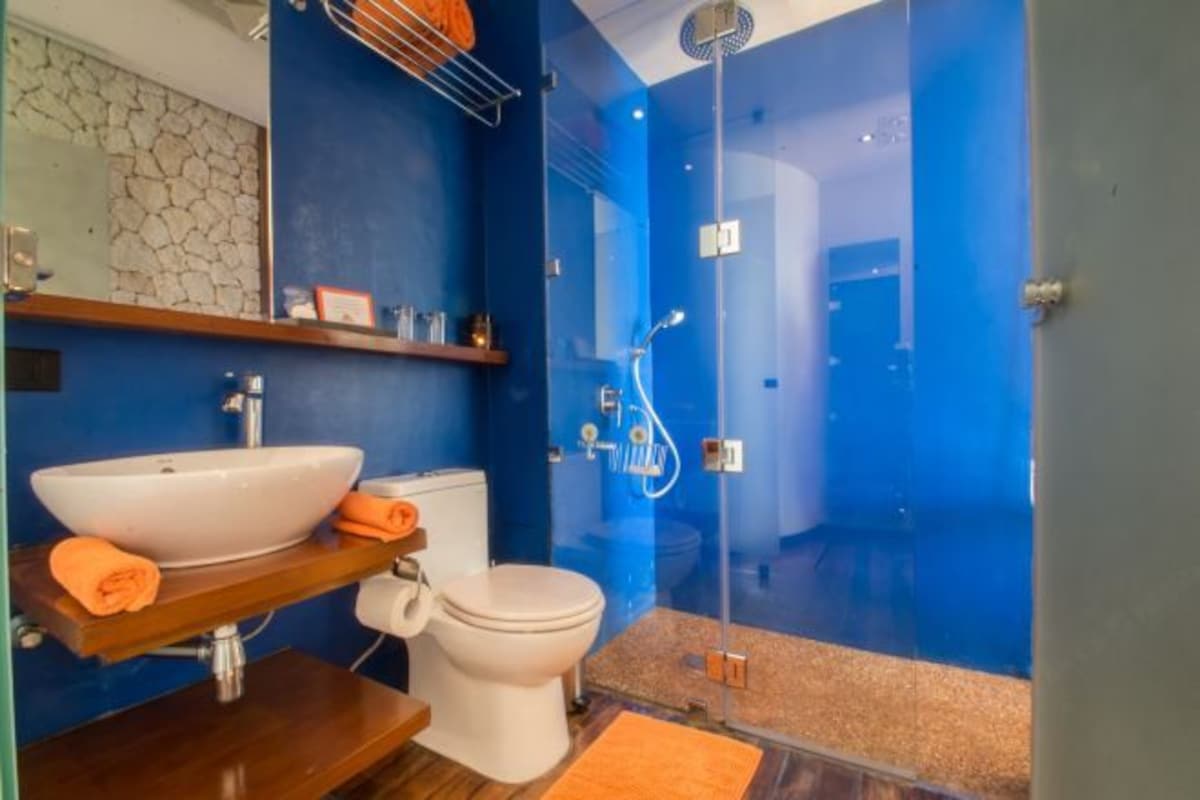 Un baño moderno con un lavamanos grande y blanco, un inodoro y una zona de ducha con cerramiento de vidrio.