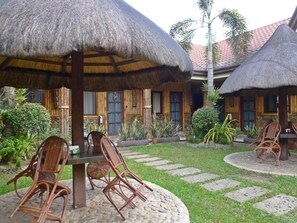 A courtyard with thatched umbrellas, wicker chairs, and a stone pathway.