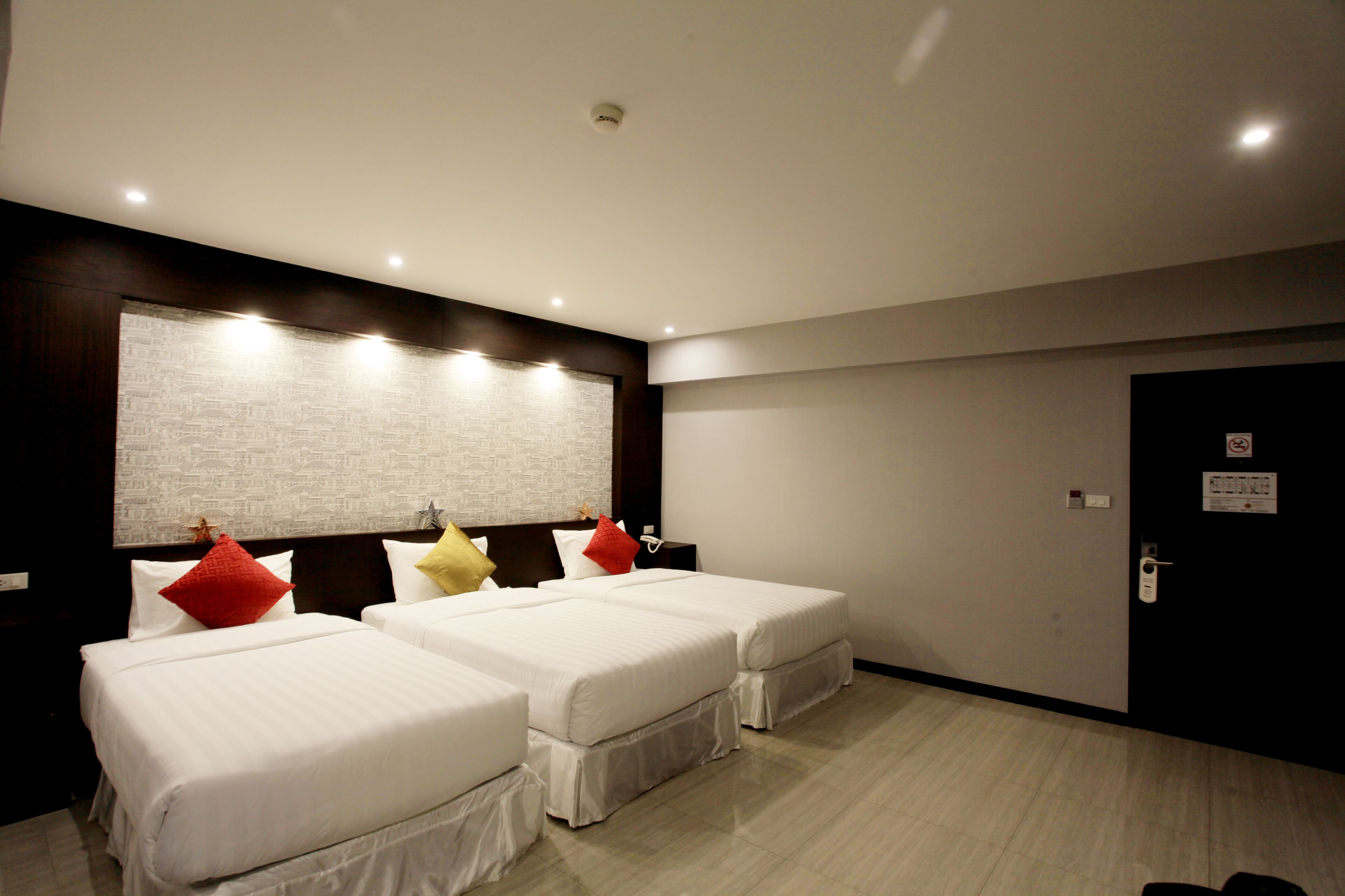 A hotel room with two beds, a large window, and a door with a sign.