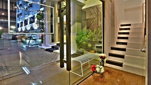Una entrada de hotel moderna con puerta de vidrio, un banco exterior y una escalera de diseño único.