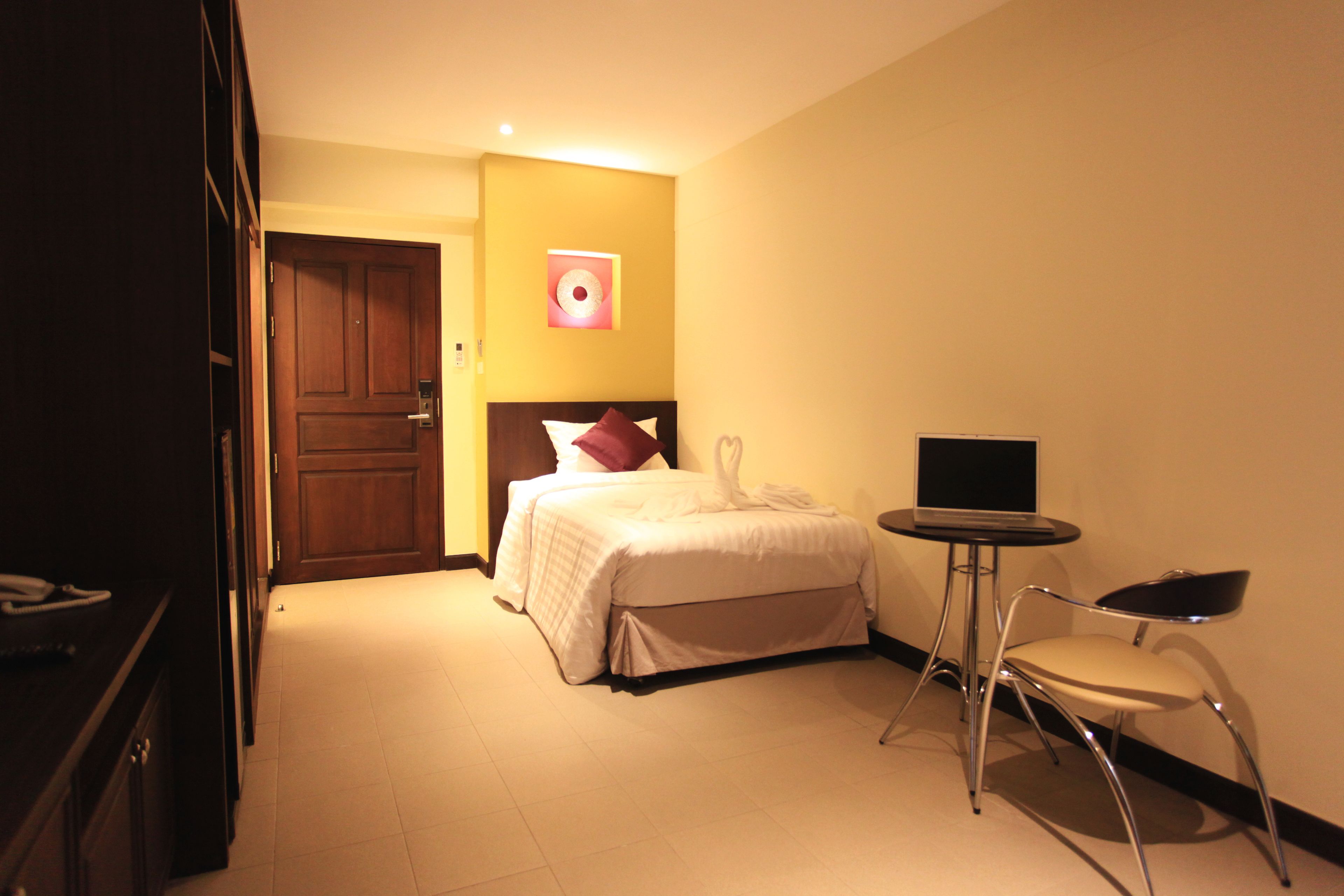 A hotel room with a bed, a desk, a chair, a TV, and a door.