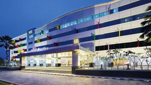 Un hôtel moderne à la façade incurvée, doté de plusieurs étages et d’une enseigne bien visible indiquant « Hôtel Santika ».