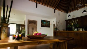 A wooden dining table with a bowl of fruit and two drinks. - Villa Nesanur (Denpasar)