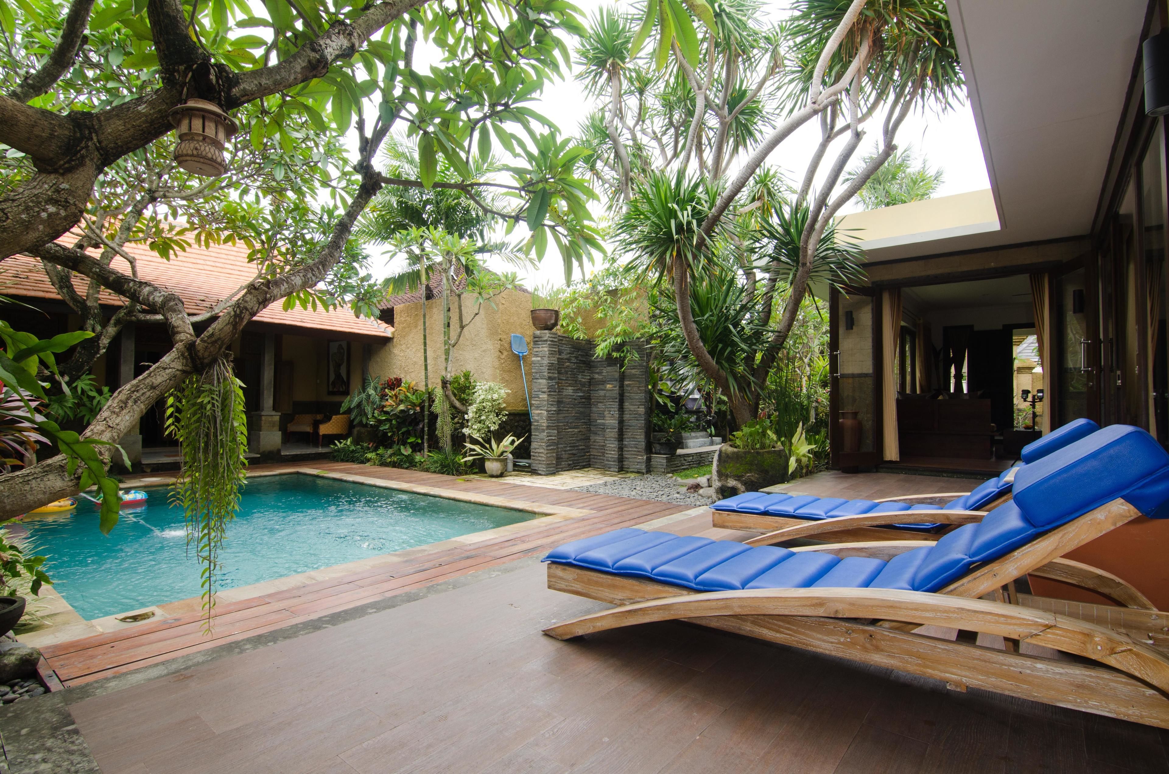 A pool area with wooden loungers and a stone wall.