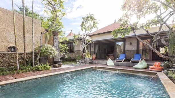 A swimming pool with lounge chairs and a covered patio area. - Villa Nesanur (Denpasar)