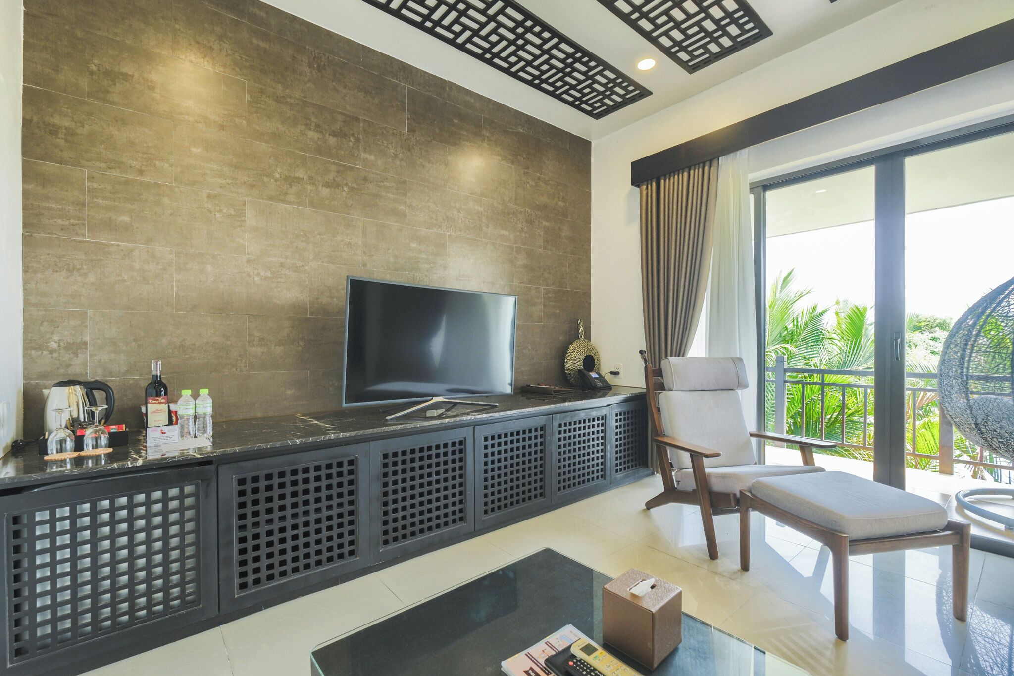 A modern living room with a flat-screen TV, a coffee machine, and a seating area with a balcony view.