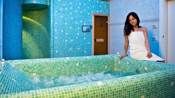 Un área de spa con una bañera grande, paredes de azulejos y una puerta de madera.