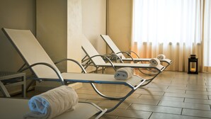 Une salle de spa équipée de fauteuils inclinables, de serviettes et d’une petite table.