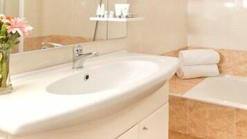 A bathroom with a sink, mirror, and bathtub.