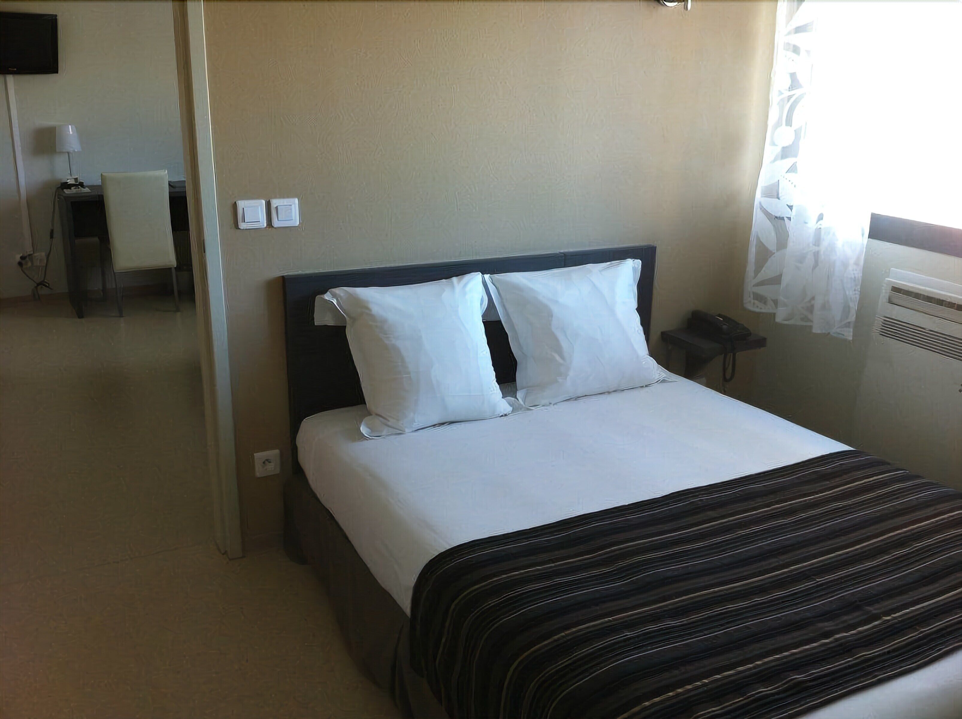 A hotel room with a bed, a nightstand, a lamp, and a telephone.