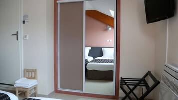 A hotel room with a sliding door closet, a bed, a chair, a TV, and a small table.