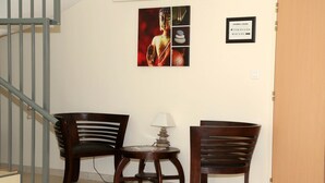 A room with a staircase, two wooden chairs, a small table with a lamp, and a wall with a Buddha statue and a sign indicating room directions. - FASTHOTEL LE RALE DES GENETS - Un hôtel FH COLLECTION  (Dun-sur-Meuse)