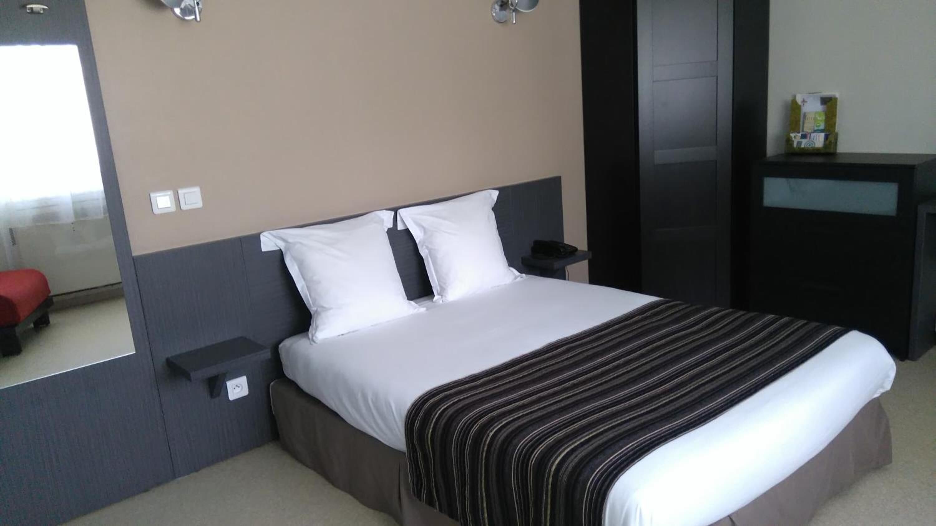 Habitación de hotel con una cama grande, una mesita de noche, un tocador y un escritorio pequeño con una silla.