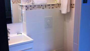 A compact bathroom with a white sink, a toilet, a hairdryer, and a towel rack.