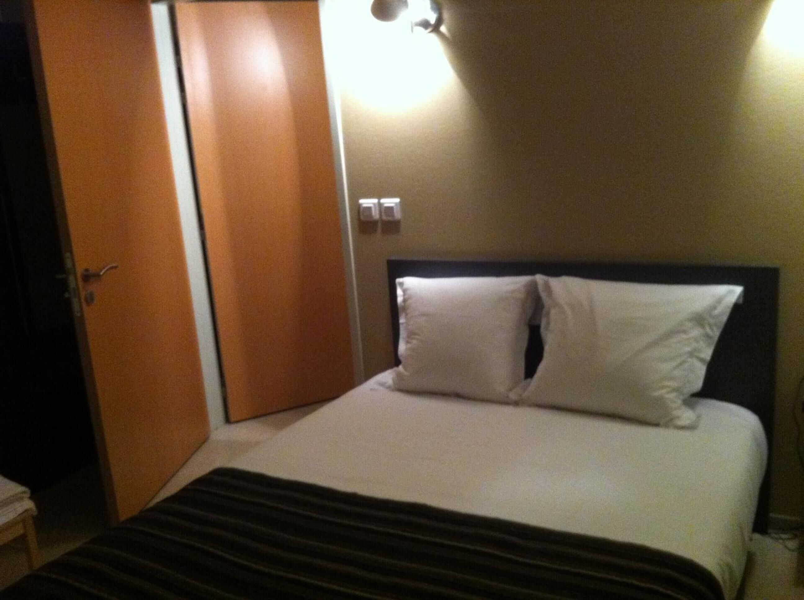 Ein Hotelzimmer mit einem Bett, einer Holztür und einer Wandleuchte.