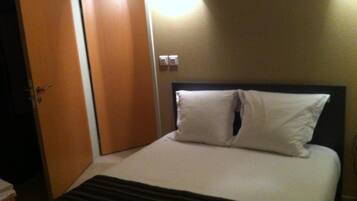 Ein Hotelzimmer mit einem Bett, einer Holztür und einer Wandleuchte.
