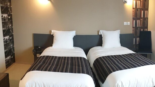 A double bed with striped bedding in a hotel room. - FASTHOTEL LE RALE DES GENETS - Un hôtel FH COLLECTION  (Dun-sur-Meuse)