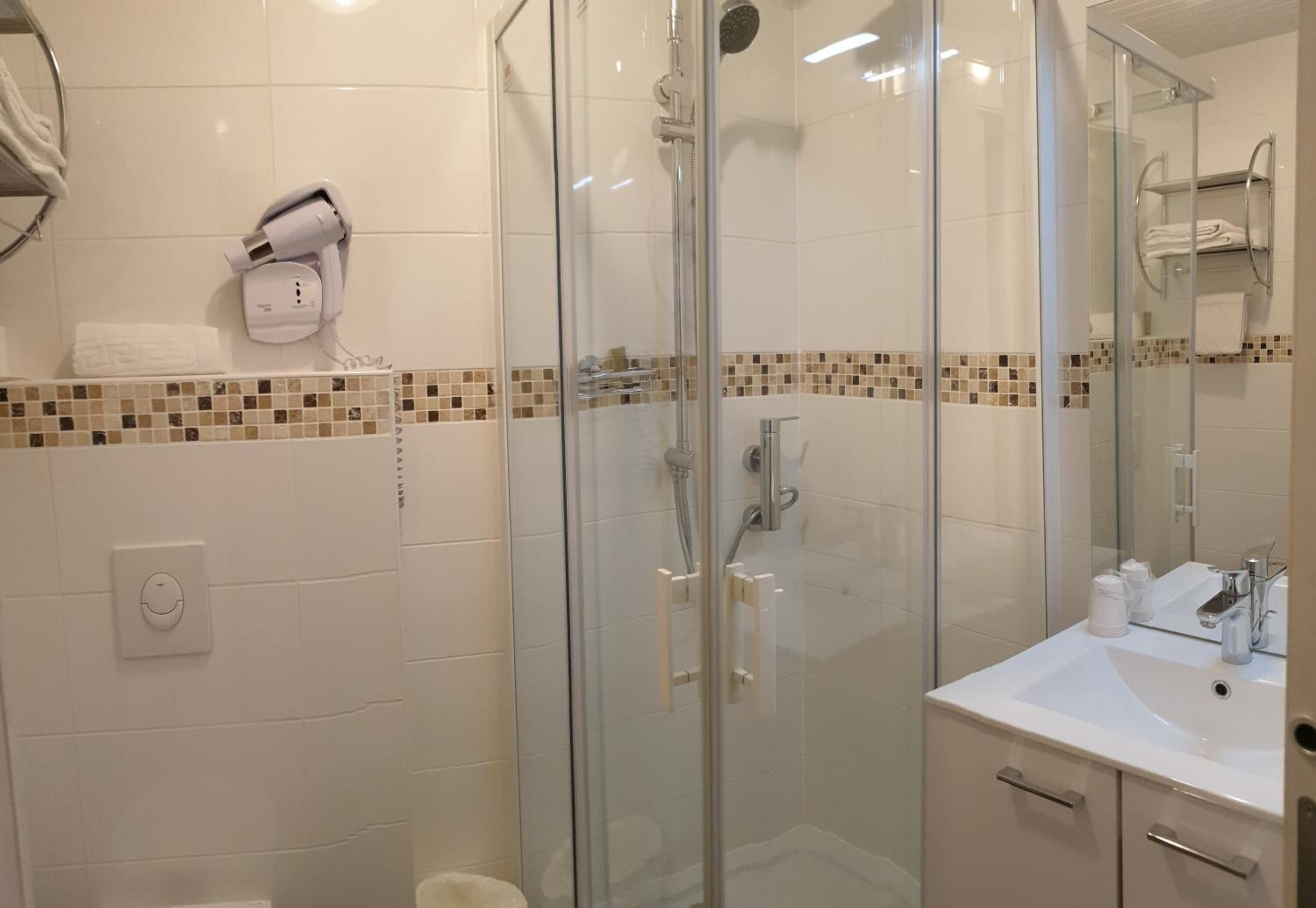 Un baño moderno con ducha de vidrio, un lavabo blanco y un perchero para toallas.