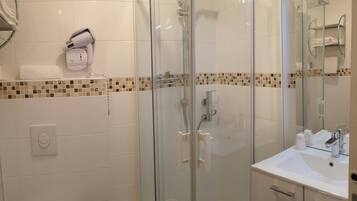 Un baño moderno con ducha de vidrio, un lavabo blanco y un perchero para toallas.