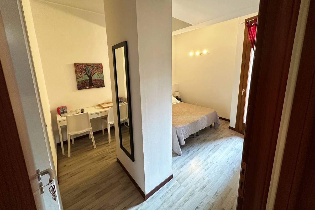 A bedroom with a bed, a desk, and a chair.