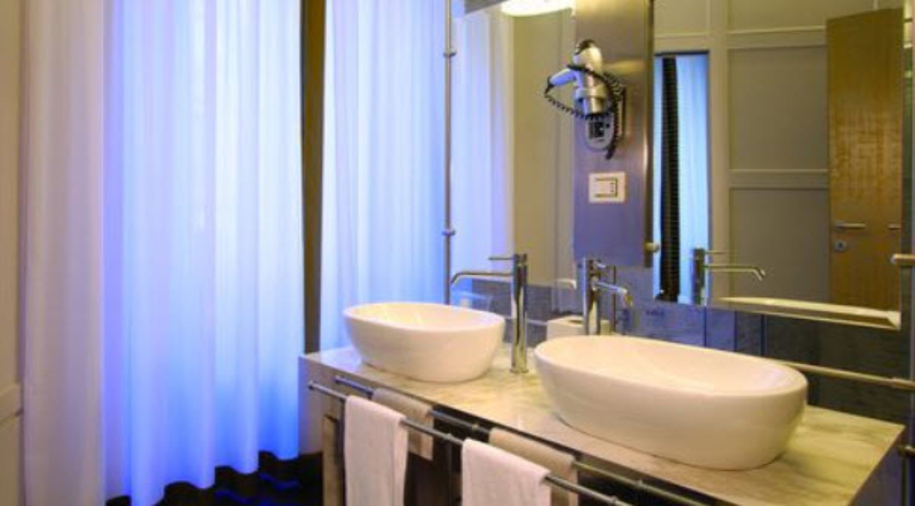 A bathroom with two sinks, a mirror, and a towel rack.