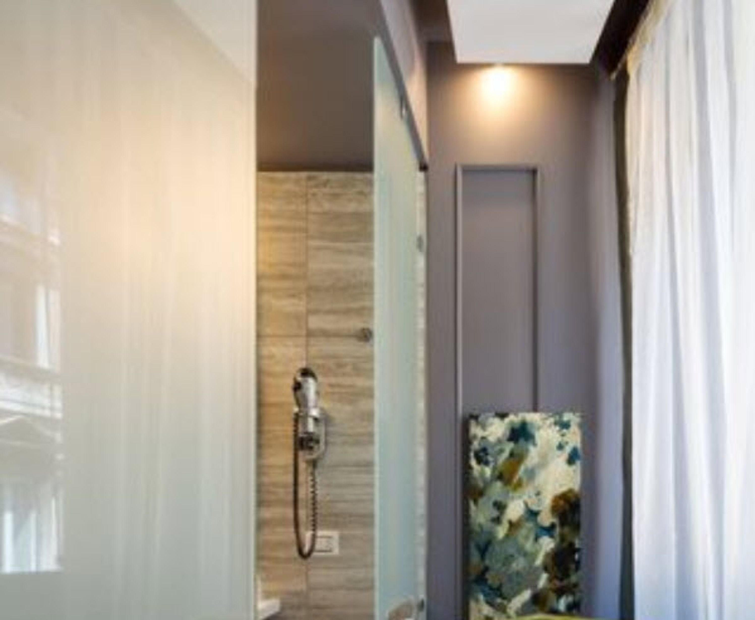 A narrow shower area with a wooden wall and a showerhead.