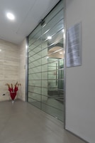 Hall moderna di un hotel con un divisorio in vetro, un portauombrelli rosso e una segnaletica che indica la posizione dell'hotel e delle sue suite.
