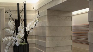 Een hoek van een gebouw met een betonnen muur en een zwarte metalen plantenbak met witte orchideeën.