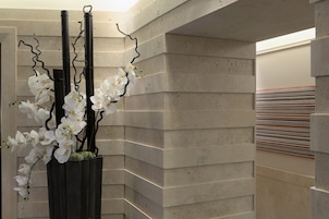 Un angolo di un edificio con un muro in cemento e un fioriere in metallo nero con orchidee bianche.