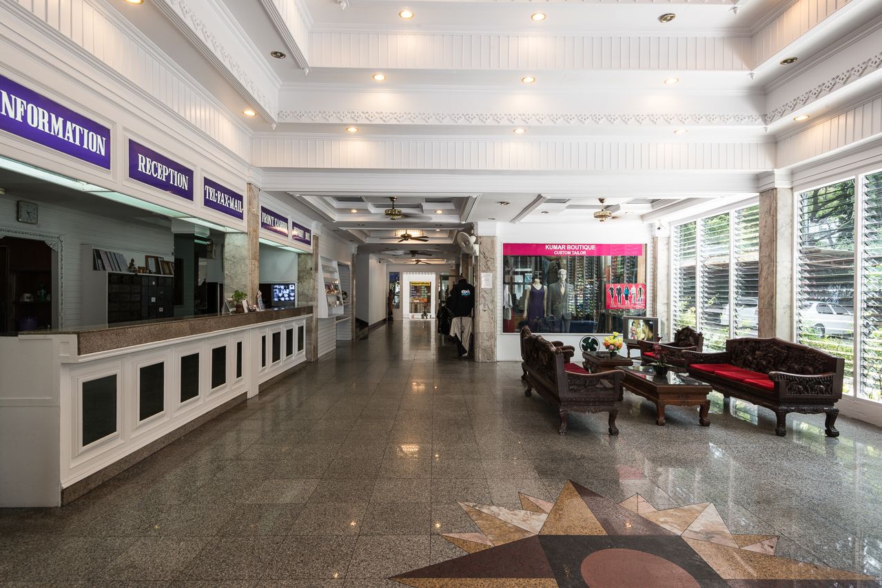 A hotel lobby with a reception desk, a payphone, and a seating area with a sofa and chairs.