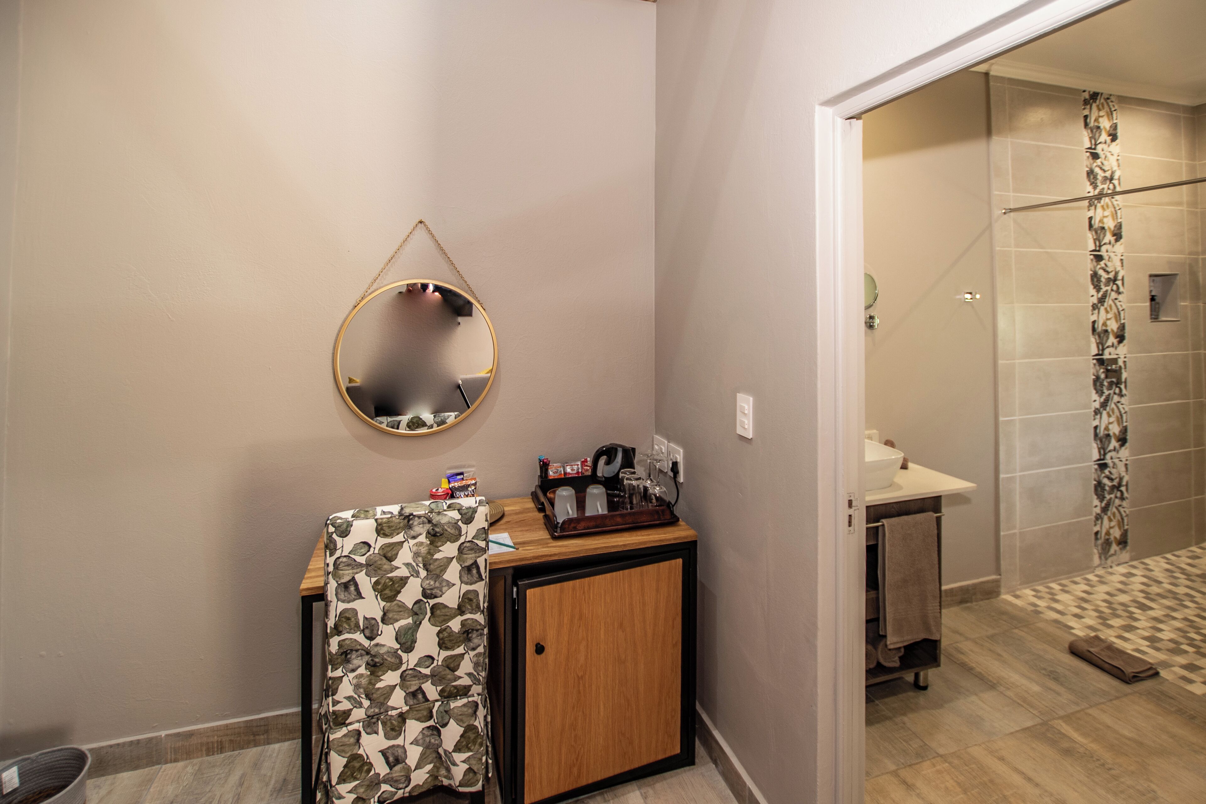 A bathroom with a wooden cabinet, a mirror, and a shower area.