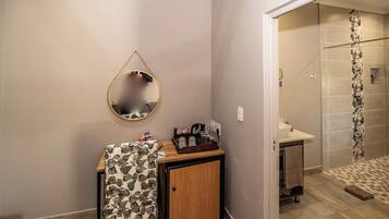 A bathroom with a wooden cabinet, a mirror, and a shower area.