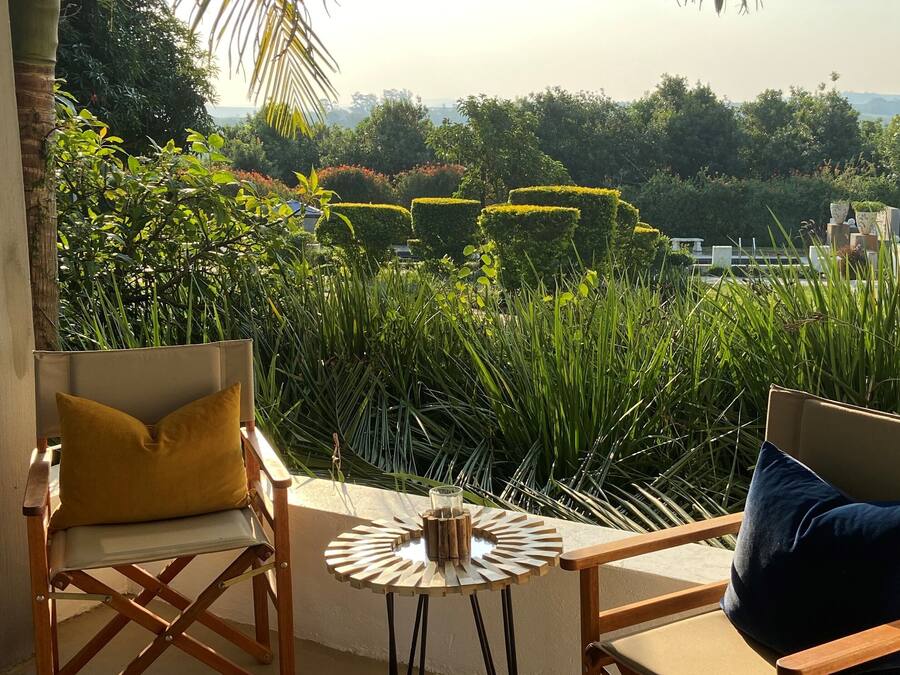 Un balcón con vistas a un jardín ajardinado, con setos cuidados y diversas plantas.
